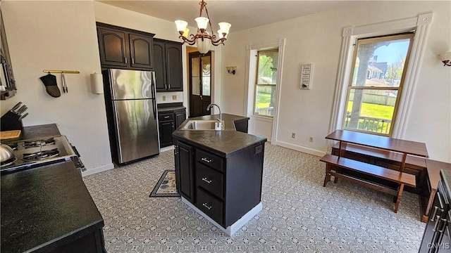 24 Grover St, Auburn, NY 13021 - kitchen with freestanding refrigerator, a sink, dark countertops, a chandelier, and an island with sink