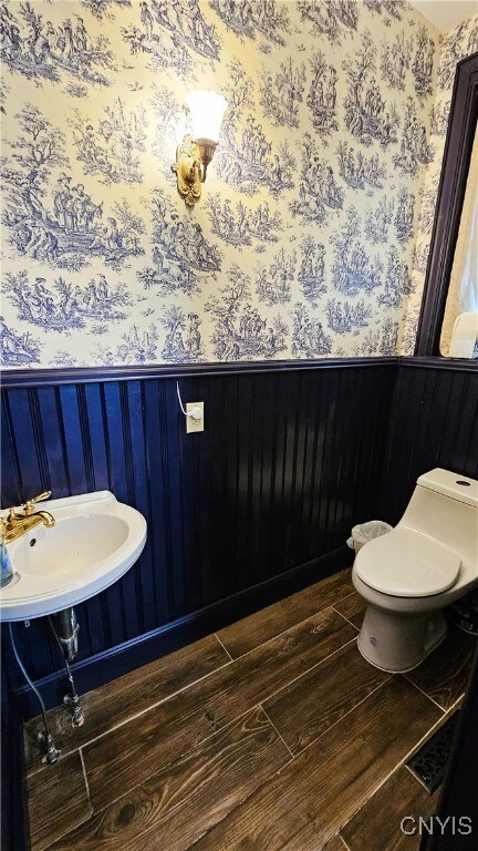 24 Grover St, Auburn, NY 13021 - half bathroom with wallpapered walls, toilet, wood finished floors, a sink, and a wainscoted wall