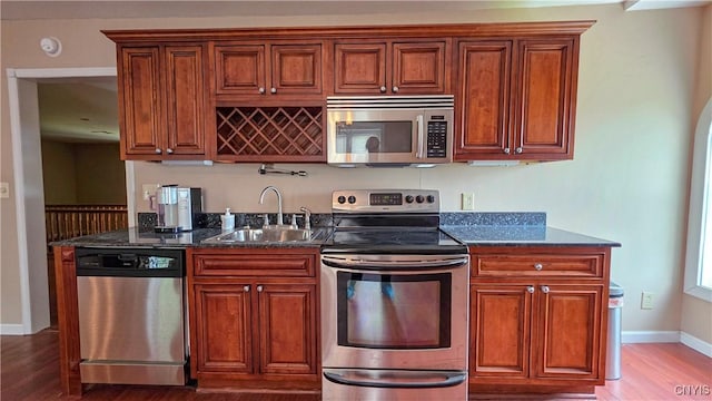 24 Grover St, Auburn, NY 13021 - kitchen featuring stainless steel appliances, light wood-style flooring, a sink, baseboards, and dark stone counters