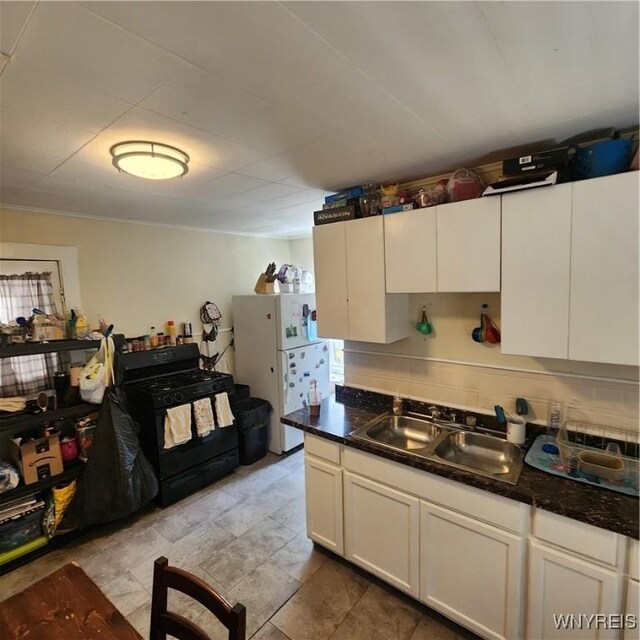 93 Austin St, Buffalo, NY 14207 - kitchen featuring black gas range oven, freestanding refrigerator, a sink, white cabinetry, and dark countertops