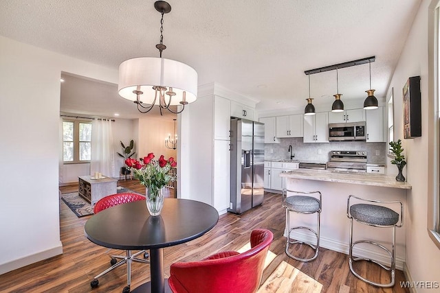 7025 Academy Ln, Lockport-Town, NY 14094 - dining area featuring a chandelier, dark wood-type flooring, baseboards, and a textured ceiling