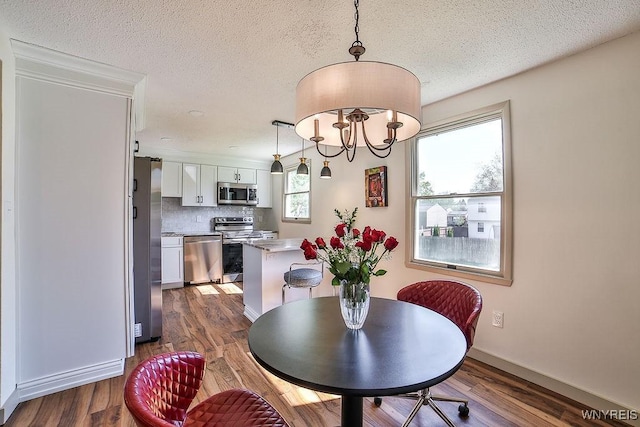 7025 Academy Ln, Lockport-Town, NY 14094 - dining area with a textured ceiling, wood finished floors, a chandelier, and baseboards