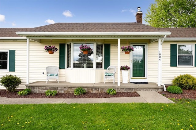 entrance to property featuring a porch, a chimney, and roof with shingles