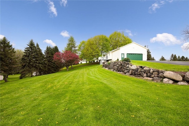 view of grassy yard featuring an attached garage and asphalt driveway