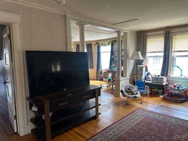 living room featuring decorative columns, wood finished floors, and crown molding