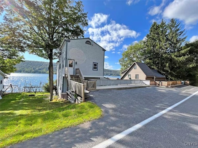 179 E Lake Rd, Deruyter, NY 13052 - view of home's exterior featuring a deck with water view, a lawn, and stairway
