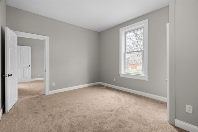 spare room featuring carpet floors and baseboards