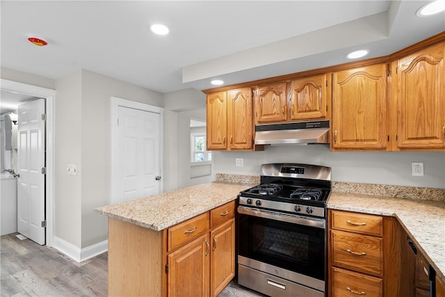 kitchen with gas stove, under cabinet range hood, light wood-style floors, light stone counters, and recessed lighting
