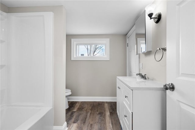 full bath with toilet, wood finished floors, baseboards, vanity, and shower / bath combination