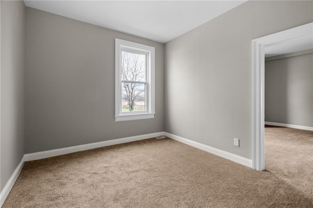 carpeted empty room featuring baseboards