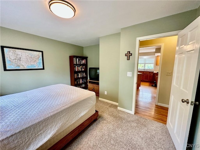 carpeted bedroom featuring baseboards and a sink