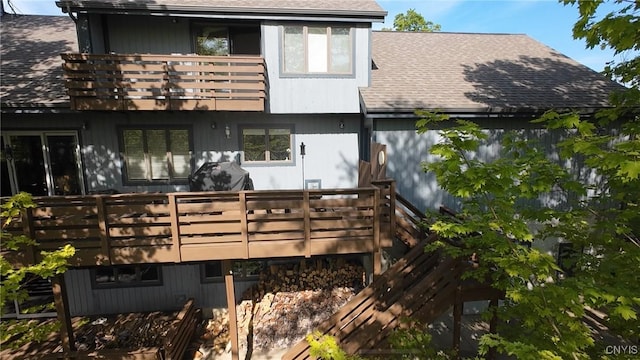 back of house with a balcony and roof with shingles