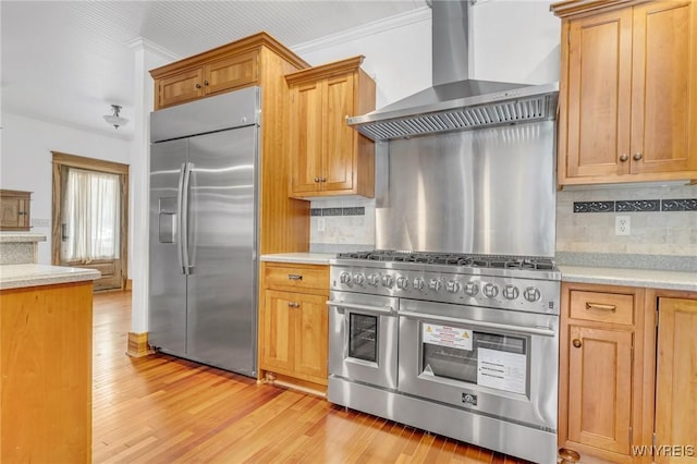 148 Mullen St, Tonawanda-City, NY 14150 - kitchen featuring stainless steel appliances, wall chimney exhaust hood, light countertops, tasteful backsplash, and light wood-style floors