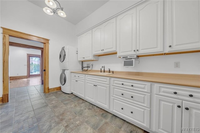 148 Mullen St, Tonawanda-City, NY 14150 - washroom featuring stacked washer / drying machine, cabinet space, baseboards, and light stone finish flooring