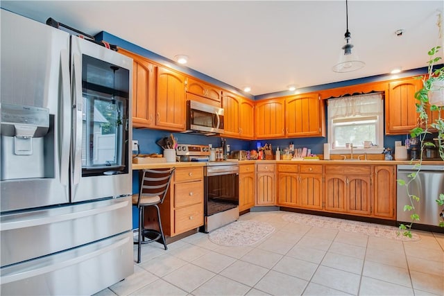 48 Division St, Maryland, NY 12155 - kitchen with stainless steel appliances, light tile patterned floors, a sink, brown cabinetry, and light countertops