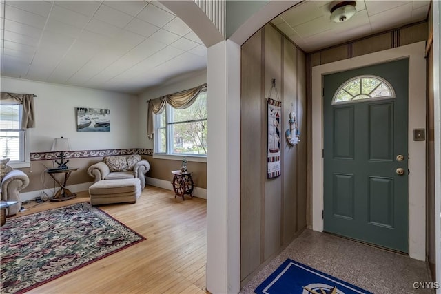 foyer entrance featuring healthy amount of natural light, light wood finished floors, arched walkways, and baseboards