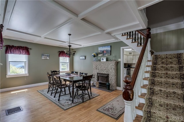 dining area featuring stairway, coffered ceiling, light wood-type flooring, baseboards, and a chandelier