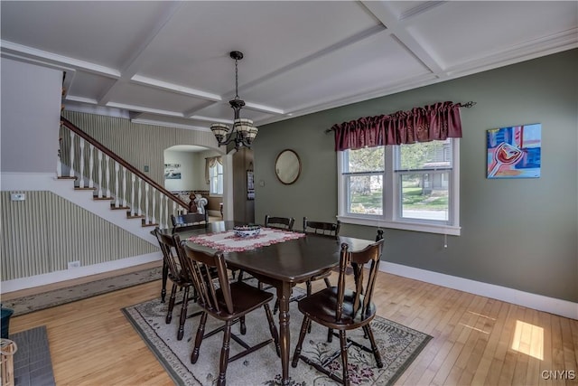 dining space featuring coffered ceiling, baseboards, arched walkways, light wood-style floors, and healthy amount of natural light
