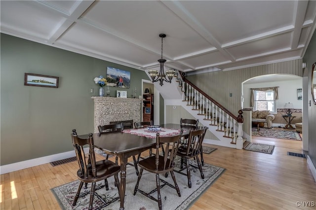 dining space with coffered ceiling, wood finished floors, a fireplace, stairs, and baseboards