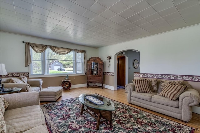 living area with arched walkways and wood finished floors