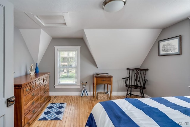 bedroom with attic access, vaulted ceiling, hardwood / wood-style flooring, and baseboards