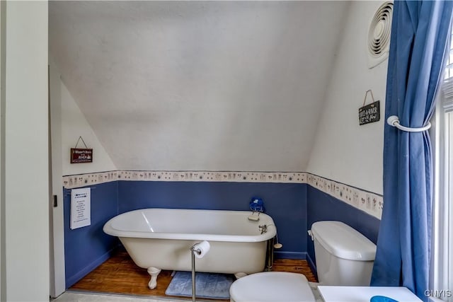 full bathroom with toilet, a freestanding tub, lofted ceiling, and wood finished floors