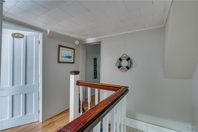 corridor with light wood-style floors, an upstairs landing, and ornamental molding