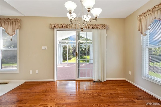 4179 Foxwood Ln, Clarence, NY 14221 - unfurnished dining area featuring a chandelier, plenty of natural light, wood finished floors, and baseboards