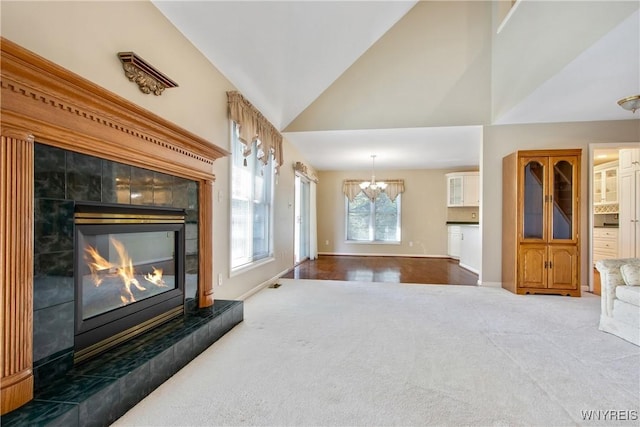 4179 Foxwood Ln, Clarence, NY 14221 - unfurnished living room featuring carpet floors, lofted ceiling, a chandelier, a tiled fireplace, and baseboards