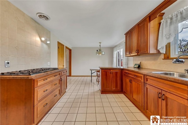 20 Post Rd, Amherst, NY 14221 - kitchen with gas stovetop, a sink, light tile patterned floors, decorative backsplash, and brown cabinets