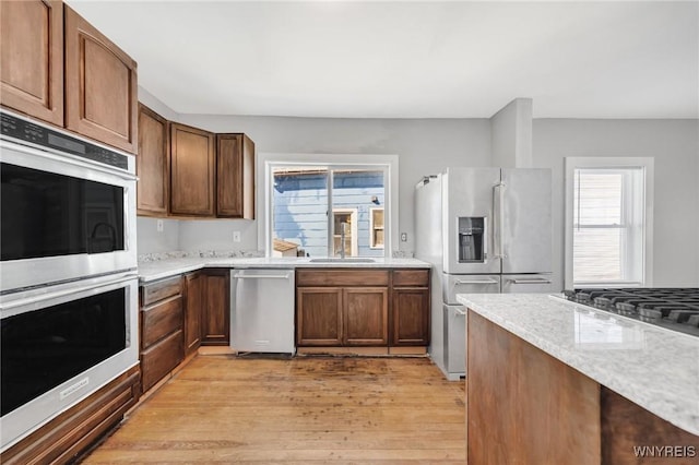 111 Roesch Ave, Buffalo, NY 14207 - kitchen featuring stainless steel appliances, light wood-style flooring, a sink, and light stone counters