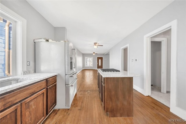 111 Roesch Ave, Buffalo, NY 14207 - kitchen featuring freestanding refrigerator, light wood-style floors, ceiling fan, a kitchen island, and brown cabinetry