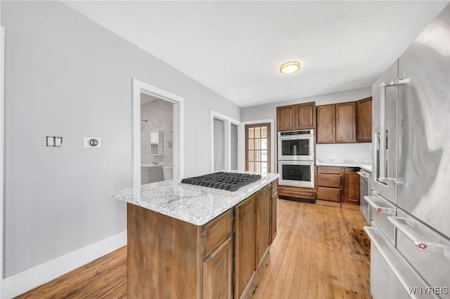 111 Roesch Ave, Buffalo, NY 14207 - kitchen with appliances with stainless steel finishes, light wood-style flooring, a kitchen island, light stone countertops, and baseboards