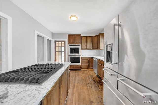 111 Roesch Ave, Buffalo, NY 14207 - kitchen featuring stainless steel appliances, brown cabinets, hardwood / wood-style flooring, and light stone counters