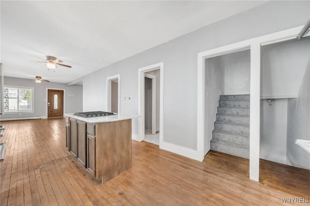 111 Roesch Ave, Buffalo, NY 14207 - kitchen featuring light wood-type flooring, a ceiling fan, stainless steel gas cooktop, a kitchen island, and light stone countertops