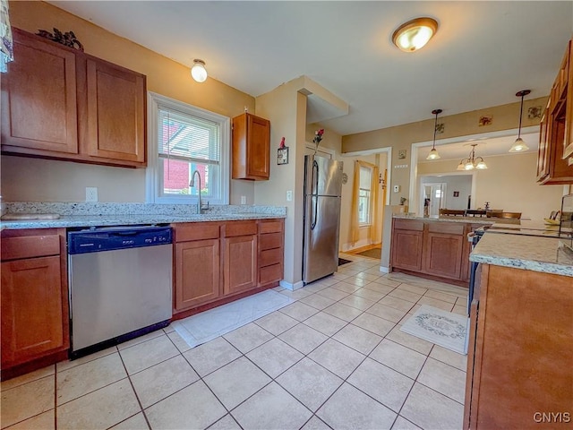 kitchen featuring stainless steel appliances, brown cabinetry, hanging light fixtures, and a sink