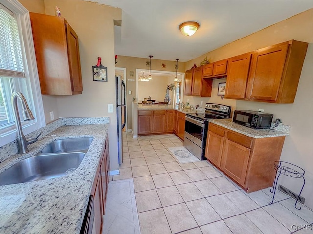 kitchen with stainless steel electric range, black microwave, a sink, freestanding refrigerator, and brown cabinets