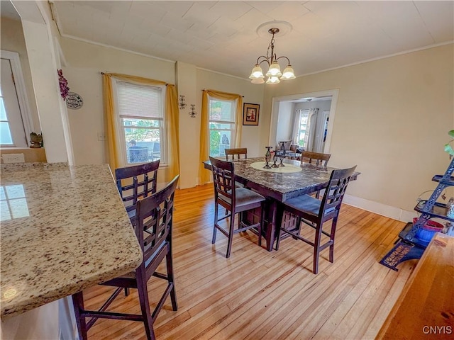 dining room featuring crown molding, light wood finished floors, plenty of natural light, and a chandelier