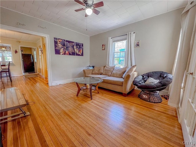 living room with light wood-type flooring, ceiling fan, and baseboards