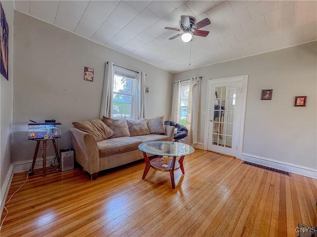 living room with ceiling fan, light wood finished floors, and baseboards