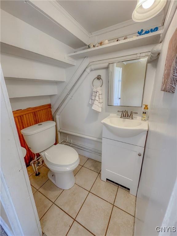 bathroom featuring tile patterned flooring, vanity, toilet, and ornamental molding