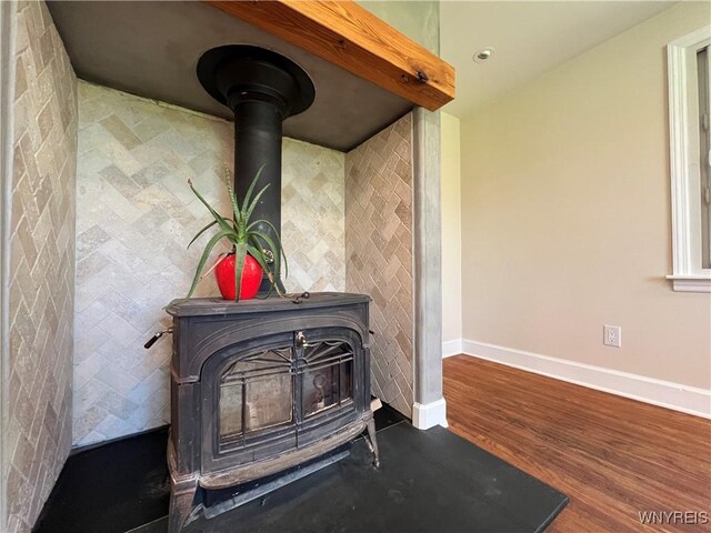 detailed view of a wood stove, baseboards, and wood finished floors