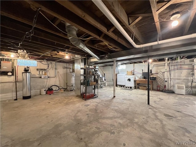 unfinished basement featuring gas water heater, washer and clothes dryer, a water softener, and heating unit