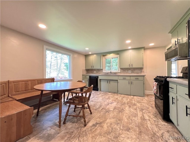 kitchen featuring black appliances, decorative backsplash, light countertops, green cabinets, and recessed lighting