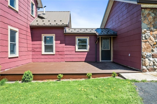doorway to property featuring a deck, a lawn, metal roof, and a standing seam roof