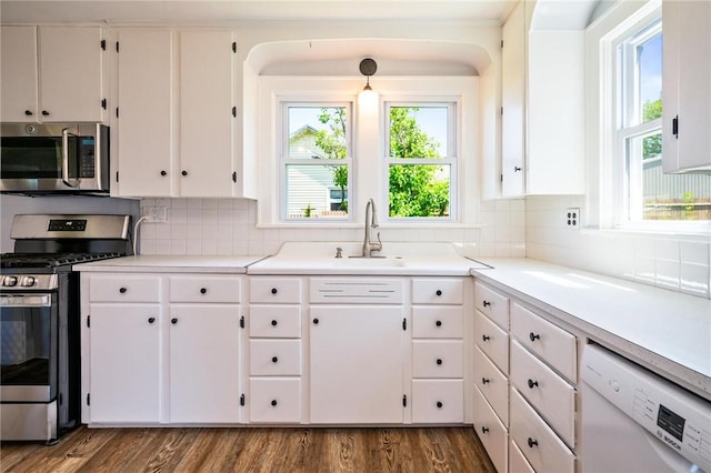 kitchen with appliances with stainless steel finishes, white cabinets, tasteful backsplash, and a sink