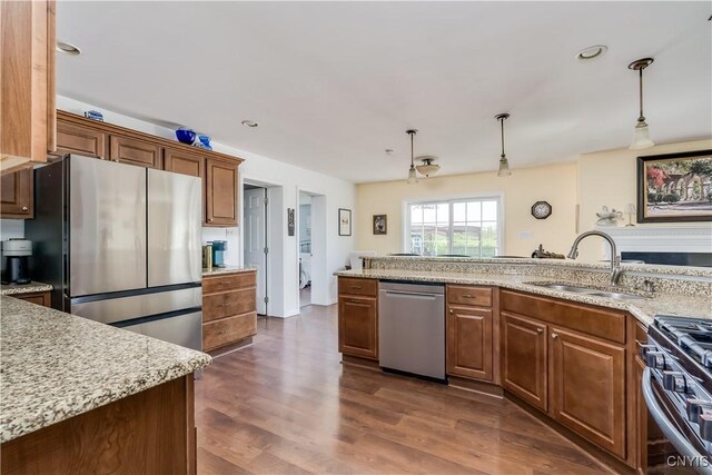 210 Funnycide Dr, Hounsfield, NY 13685 - kitchen featuring appliances with stainless steel finishes, a sink, dark wood finished floors, decorative light fixtures, and brown cabinetry