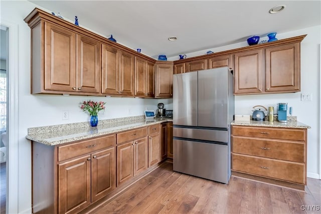 210 Funnycide Dr, Hounsfield, NY 13685 - kitchen with freestanding refrigerator, light wood finished floors, brown cabinets, light stone counters, and recessed lighting