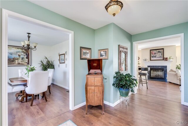 210 Funnycide Dr, Hounsfield, NY 13685 - dining area featuring a chandelier, wood finished floors, a fireplace with flush hearth, and baseboards