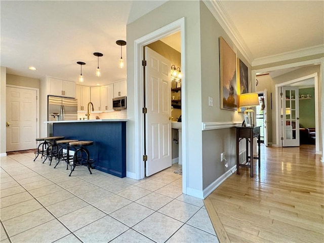 214 Fairfield Dr, Horseheads, NY 14845 - kitchen featuring stainless steel appliances, a kitchen bar, a peninsula, white cabinets, and ornamental molding